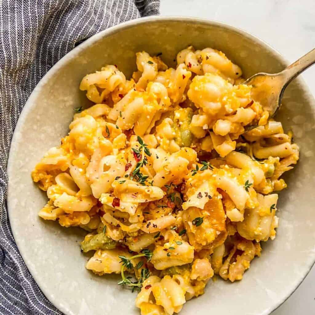 Butternut squash feta pasta in an offwhite bowl next to a blue napkin.