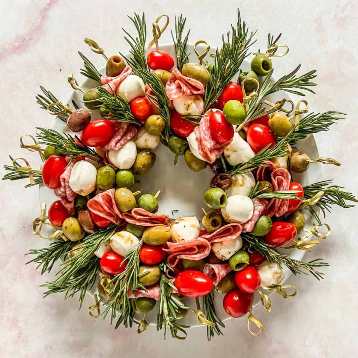 Christmas antipasto wreath skewers on a white plate.