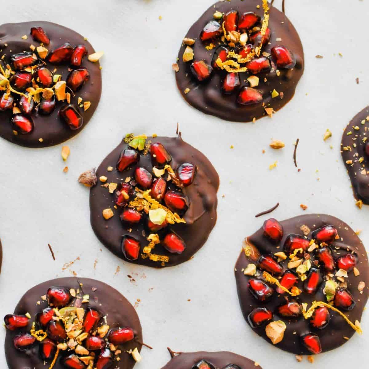Dark chocolate pomegranate treats on a piece of parchment.