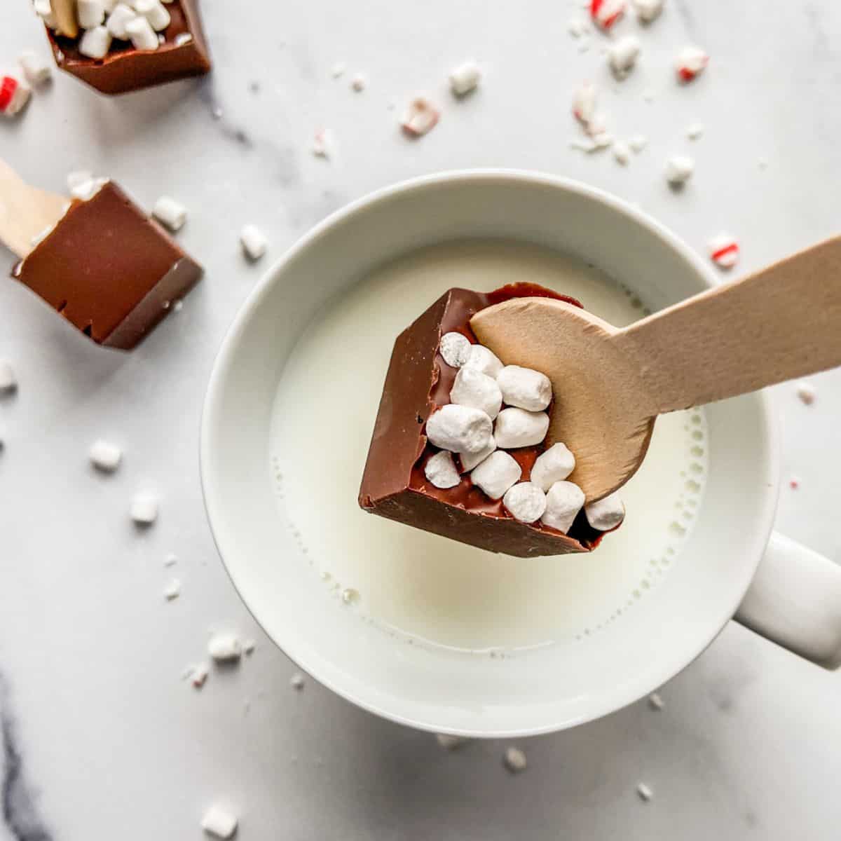 Hot chocolate spoon being dipped into milk.