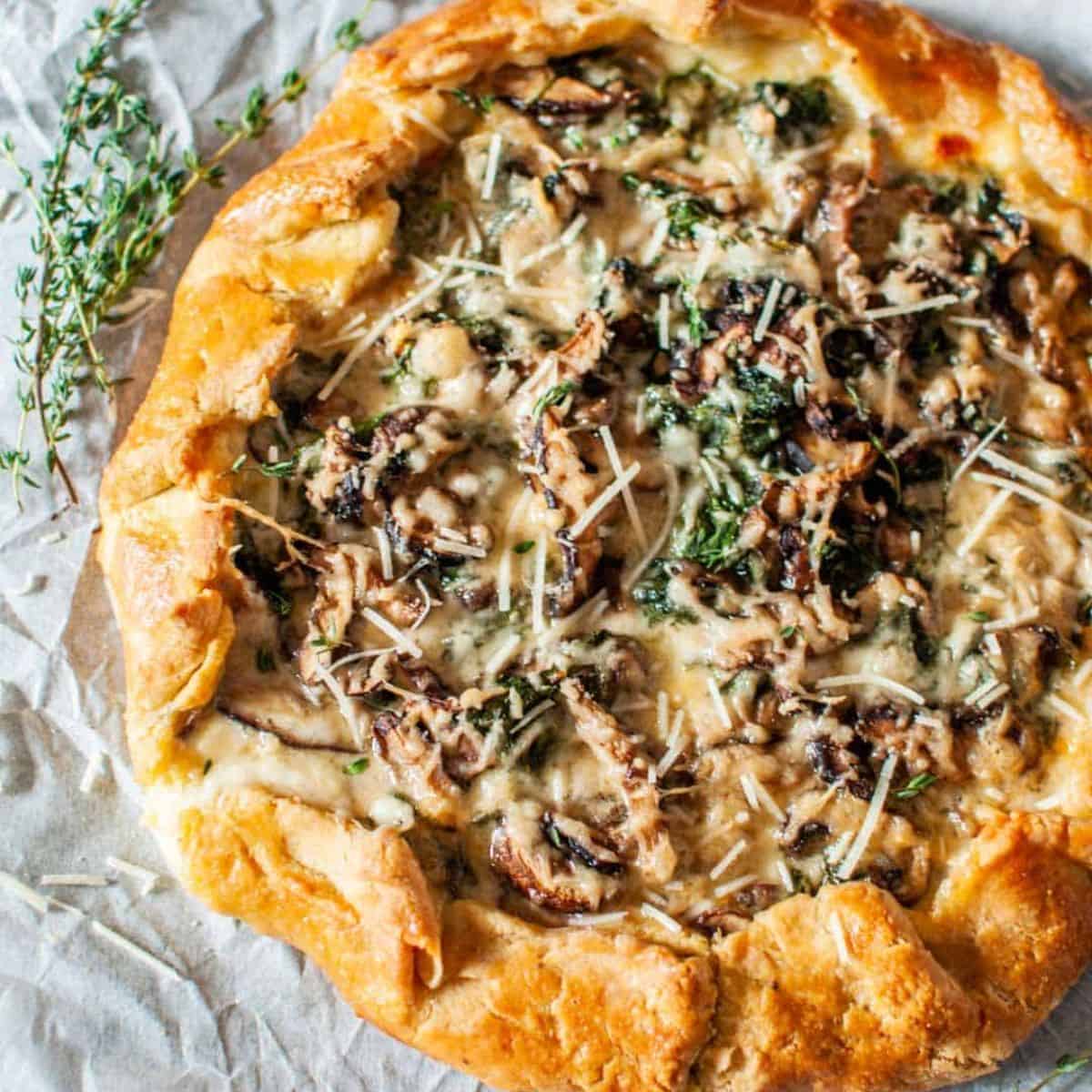 Spinach mushroom galette on a sheet of parchment paper.