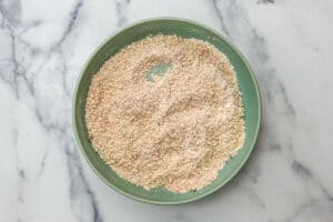 A large green dish with parmesan, spices, and flour.