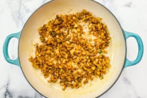 Onions, pepper, and spices cooking in a enameled pan.