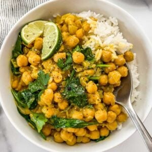 Chickpea curry and white rice in a white bowl with a silver spoon.