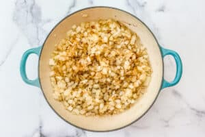 Onions being cooked in a enameled skillet.