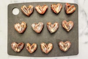 Halved dates pressed together to look like hearts on a cutting board.