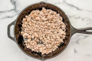 Cooked ground pork in a cast iron skillet.