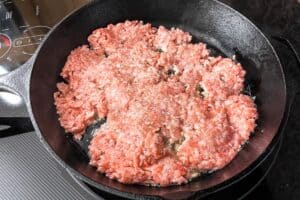 Ground pork cooking in a cast iron skillet.