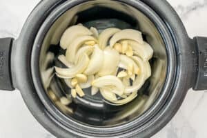 Sliced onions and chopped garlics in a slow cooker.