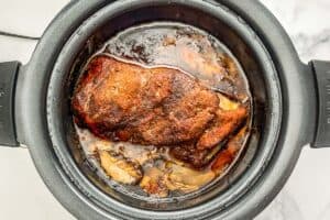 Cooked pork shoulder in a slow cooker.