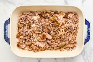 Shredded slow cooker carnitas in a large pan.