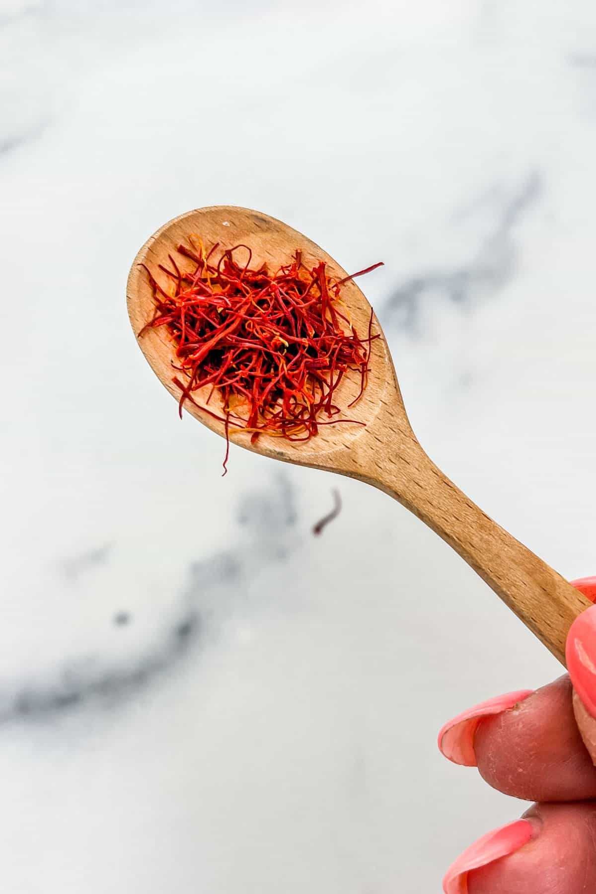 Saffron strands on a wooden spoon.