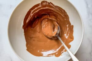 Melted chocolate in a white bowl with a spoon.