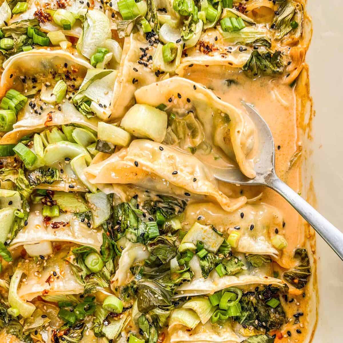 One pan coconut milk dumpling bake topped with bok choy and scallions.