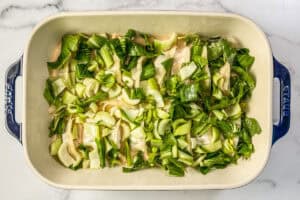 Dumplings, bok choy, and coconut milk in a casserole dish.