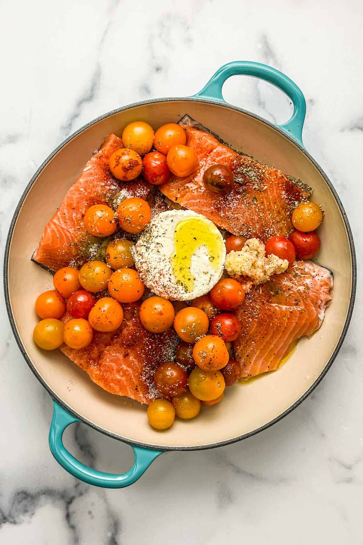 Salmon fillets, boursin cheese, cherry tomatoes, spices, and olive oil in a enamel pot.