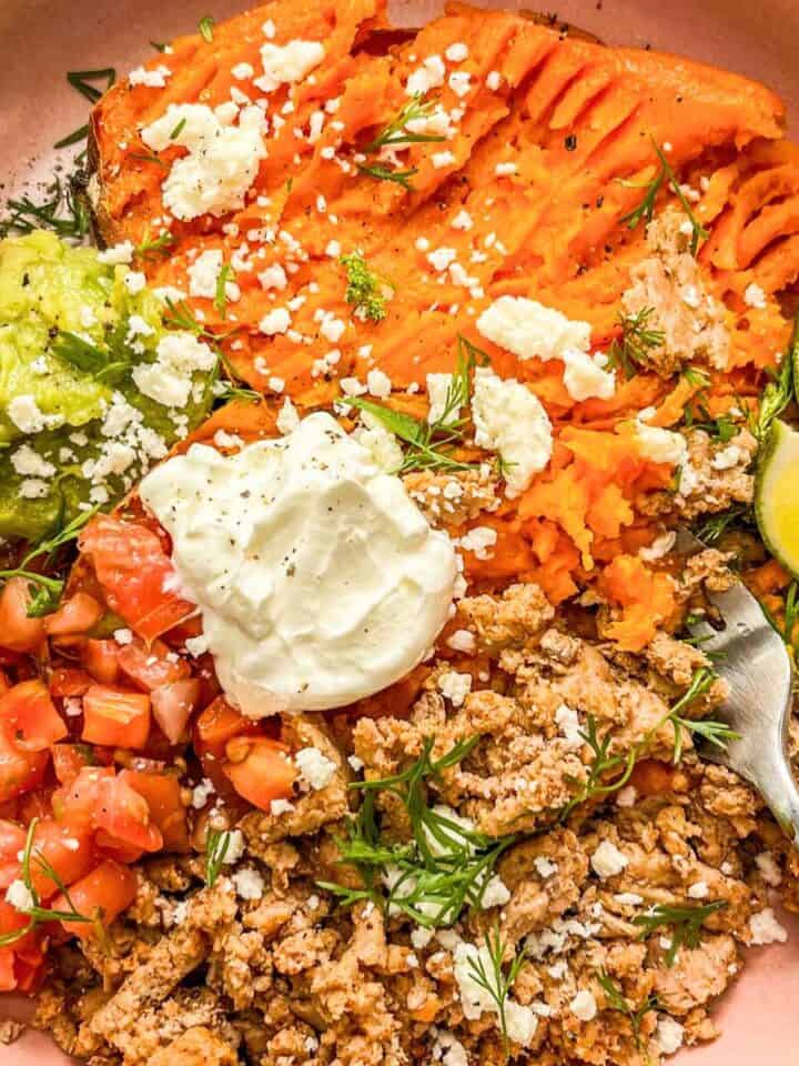 Ground turkey sweet potato bowl toped with sour cream, guacamole, and crumbled cheese.