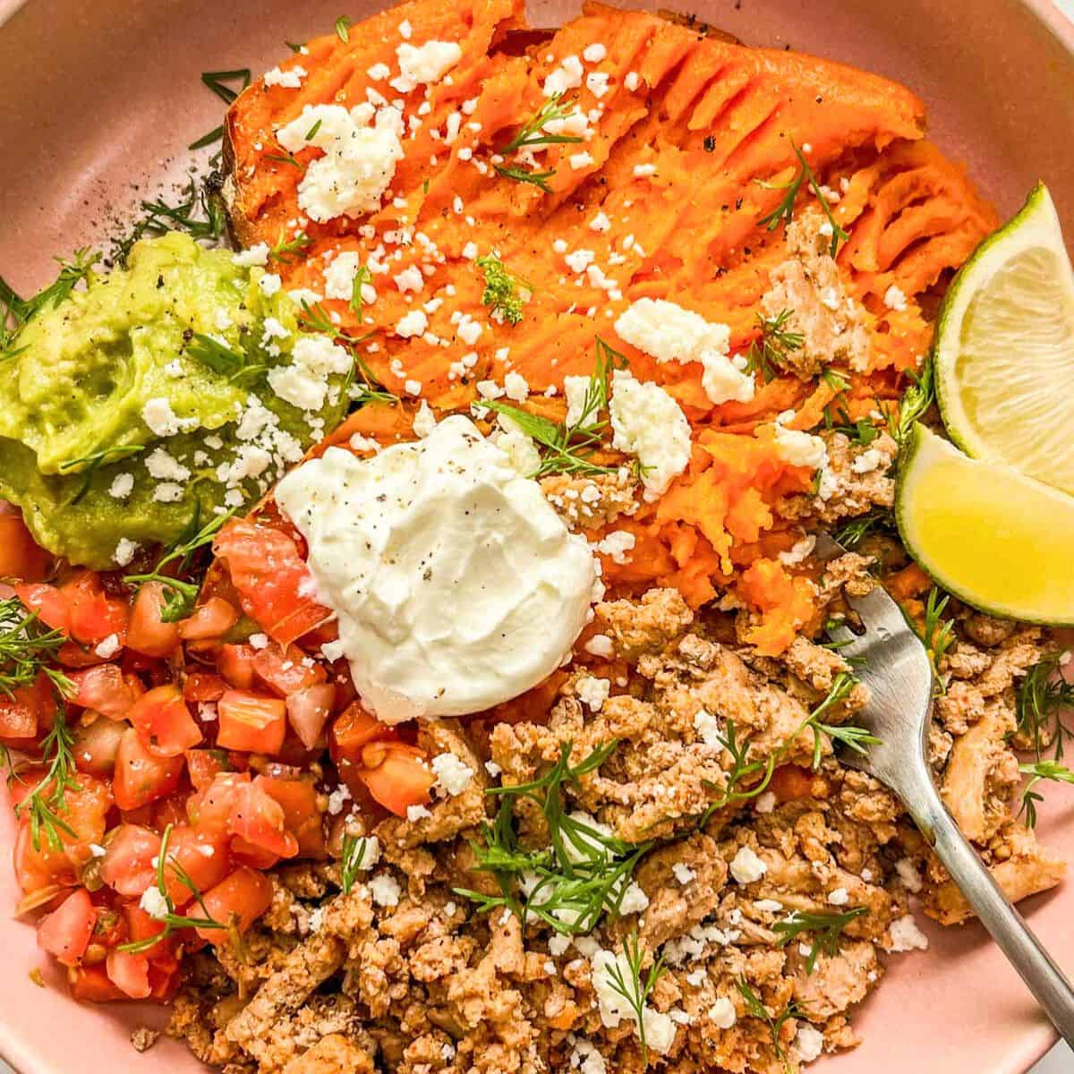 Ground turkey sweet potato bowl toped with sour cream, guacamole, and crumbled cheese.