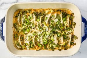 A 9x13 inch casserole dish with baked dumplings in a creamy sauce, topped with bok coy and green onions.