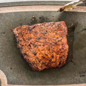 Grilled flank steak on a black cutting board.