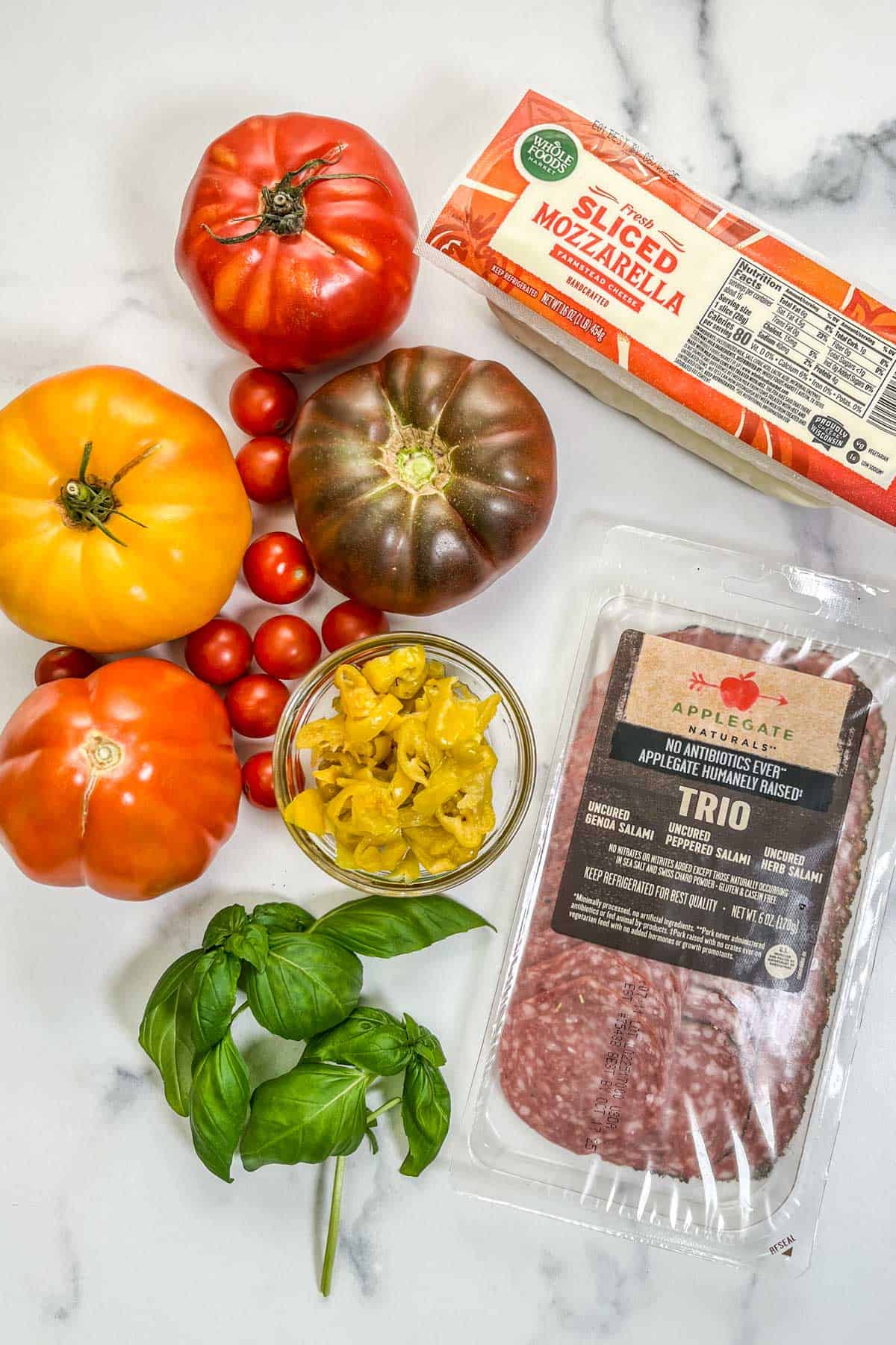 Antipasto salad ingredients on a marble background.