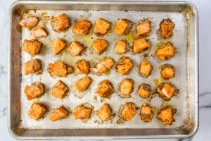Cooked salmon chunks on a silver sheet pan.
