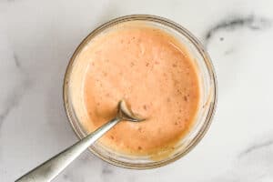 Bang bang sauce in a glass bowl with a silver spoon.