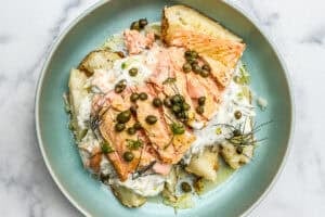 Salmon baked potato with dill sauce in a blue bowl.
