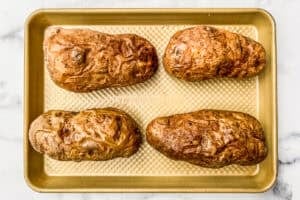 Four roasted potatoes on a sheet pan.