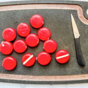 Babybel cheeses with the wrappers removed on a cutting board.