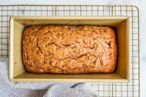 Cantaloupe bread in a gold bread pan on a cooling rack.