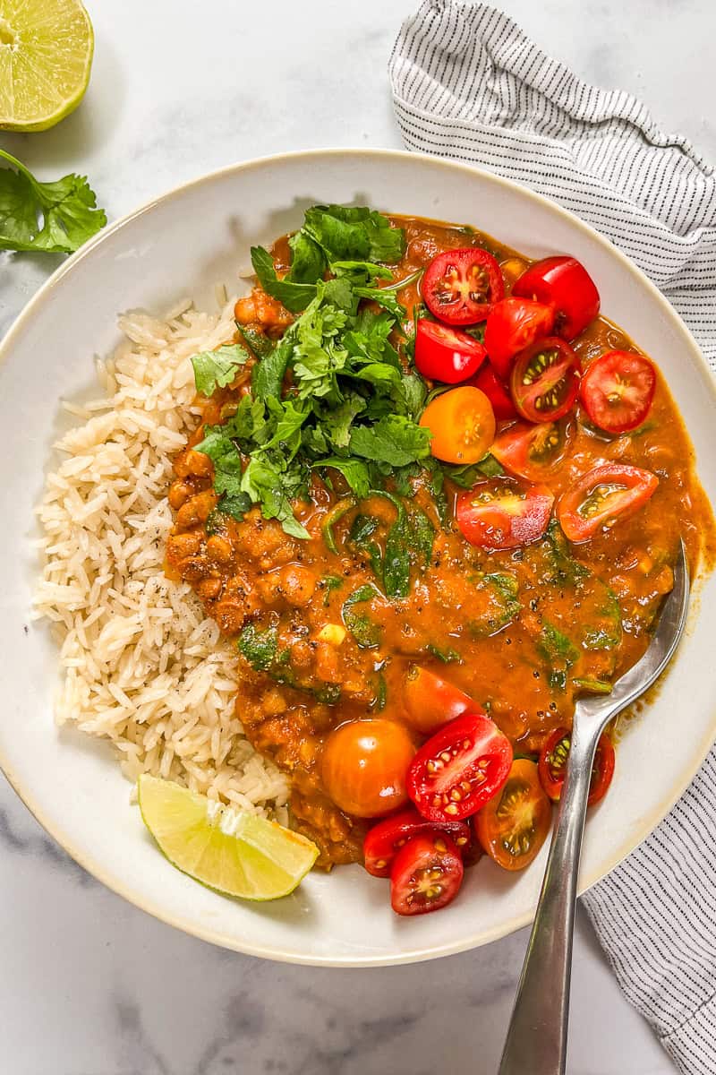 Coconut lentil curry with rice in a white bowl with a silver spoon.