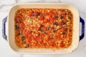 Baked orzo, chickpeas, olives, feta, and tomatoes in a baking dish.
