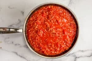 Tomatoes, onion, and pancetta cooking in a frying pan.