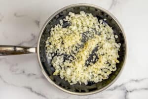 Onions and garlic being cooked in a skillet.