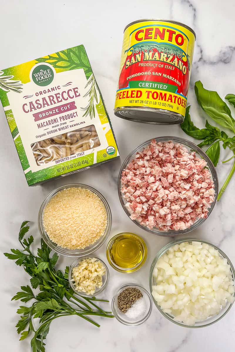 Ingredients for pasta with pancetta on a marble background.