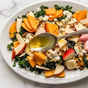 Dressing being spooned onto persimmon pear salad.