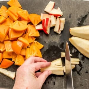 Sliced pears and persimmon on a black cutting board.