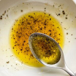 Vinaigrette in a white bowl with a spoon.