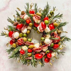 Christmas antipasto wreath with rosemary on a white plate.