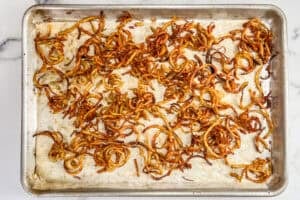 A parchment lined sheet pan with baked curly fries.