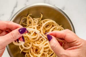 Spiralized potato slices being torn in half.