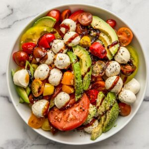 Tomatoes, avocado, and mozzarella topped with balsamic glaze, salt, and pepper.