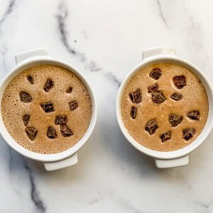 Chocolate oat batter topped with chocolate chunks in two ramekins.