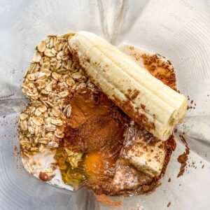 Oats, banana, cocoa, and an egg in a blender.