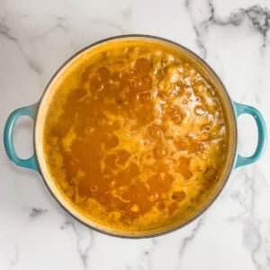 Broth, pumpkin, butter beans, spices, and onion simmering in a pot.