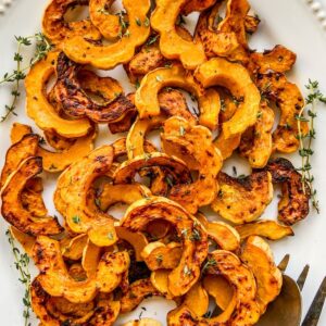 Roasted delicata squash slices on a white platter.