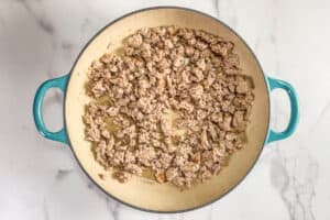 Cooked ground turkey in a skillet with teal handles.
