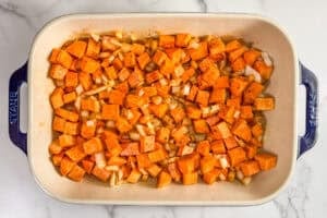 Baked sweet potatoes chunks and diced onions in a large baking dish.
