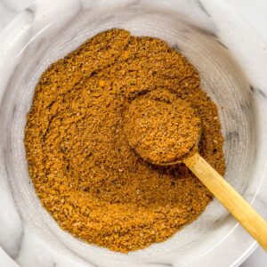 Hawaij spice blend in a marble bowl with a gold spoon.